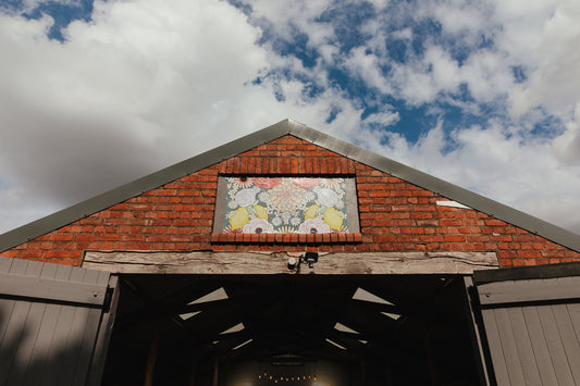 Barn wedding venue with blue sky above and a floral sign above the open doors.